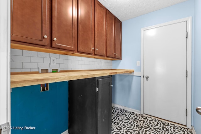 kitchen with decorative backsplash, a textured ceiling, and wood counters