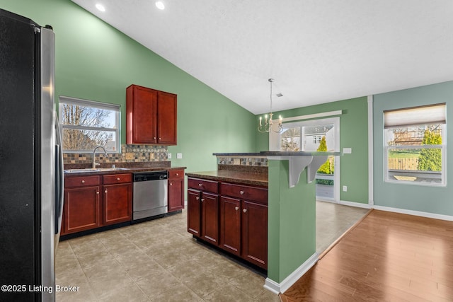 kitchen featuring pendant lighting, appliances with stainless steel finishes, a notable chandelier, vaulted ceiling, and a breakfast bar