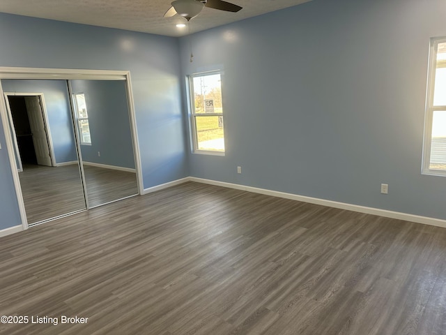 unfurnished bedroom featuring ceiling fan, a closet, dark wood-type flooring, and a textured ceiling