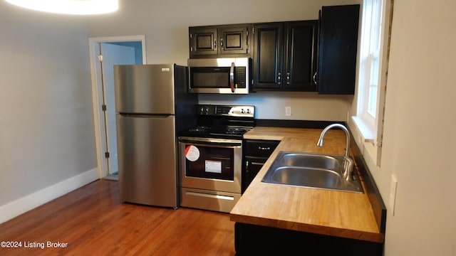 kitchen featuring butcher block countertops, sink, appliances with stainless steel finishes, and hardwood / wood-style floors