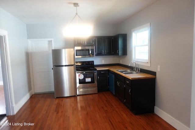 kitchen featuring appliances with stainless steel finishes, dark hardwood / wood-style flooring, hanging light fixtures, and sink