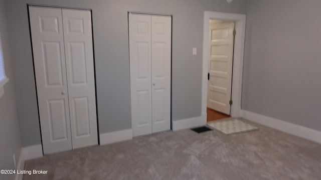 unfurnished bedroom featuring carpet floors and multiple closets