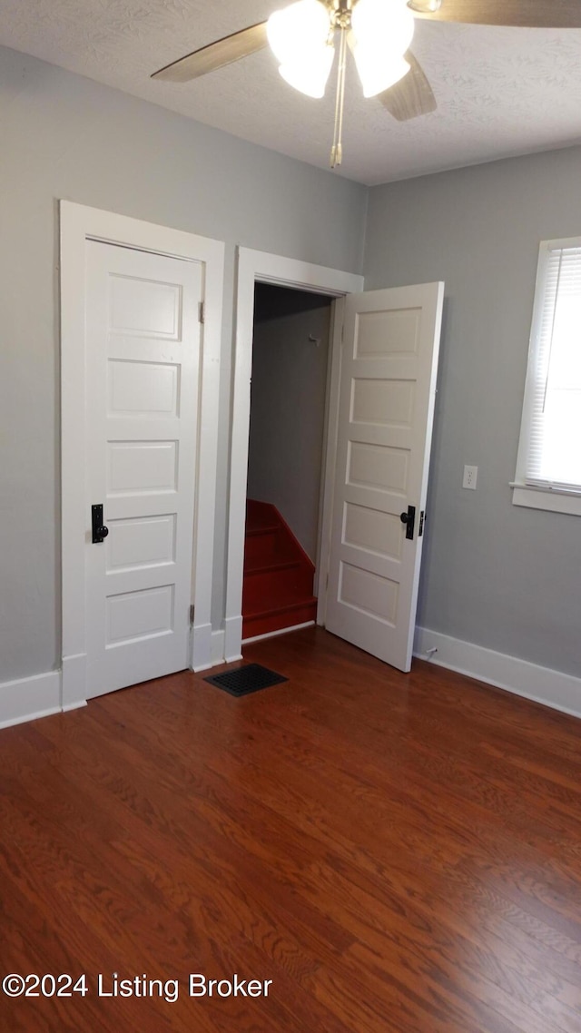 unfurnished bedroom with ceiling fan, dark hardwood / wood-style flooring, a textured ceiling, and a closet