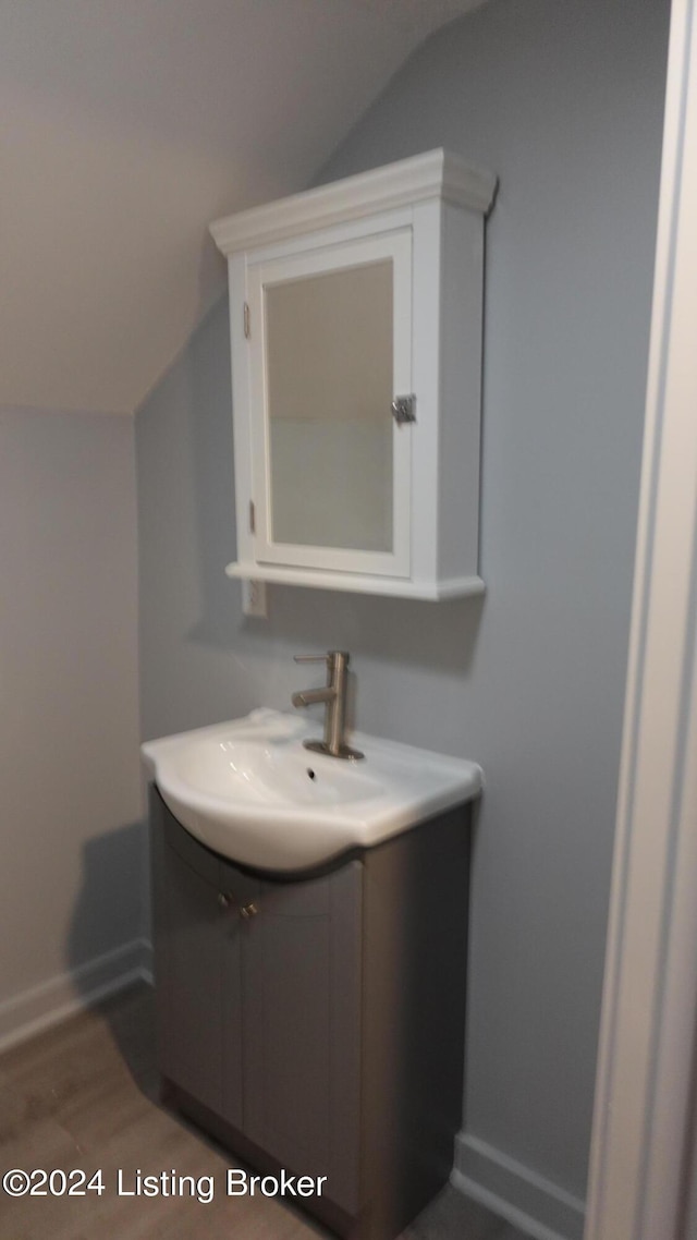 bathroom featuring wood-type flooring, vanity, and lofted ceiling