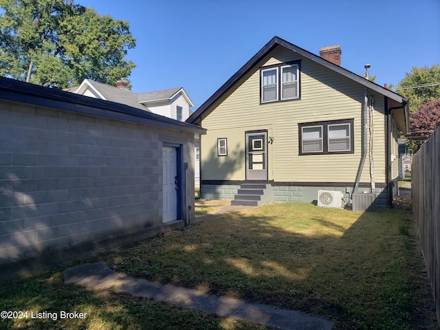 rear view of house featuring ac unit and a yard