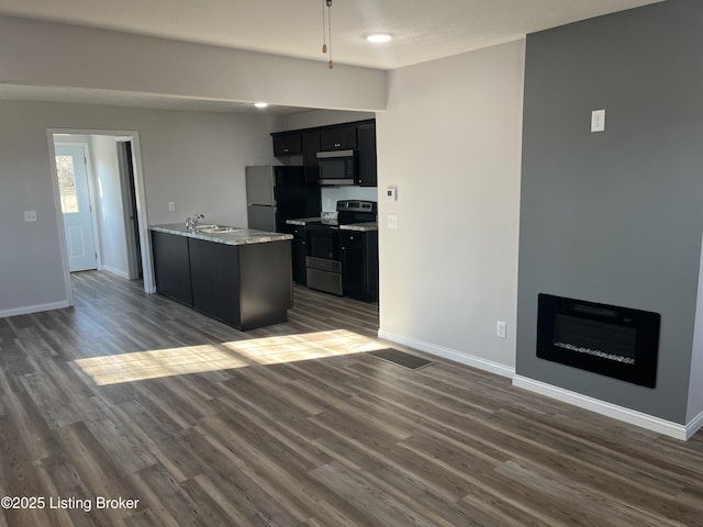 kitchen featuring light stone countertops, appliances with stainless steel finishes, dark hardwood / wood-style floors, and sink