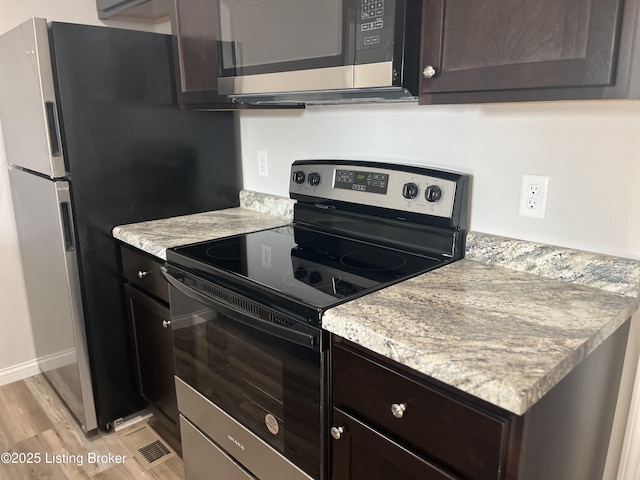 kitchen featuring light stone countertops, dark brown cabinets, stainless steel appliances, and light hardwood / wood-style floors