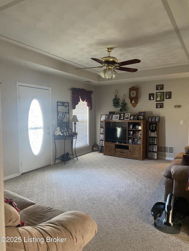 living area featuring carpet, visible vents, a tray ceiling, and ceiling fan