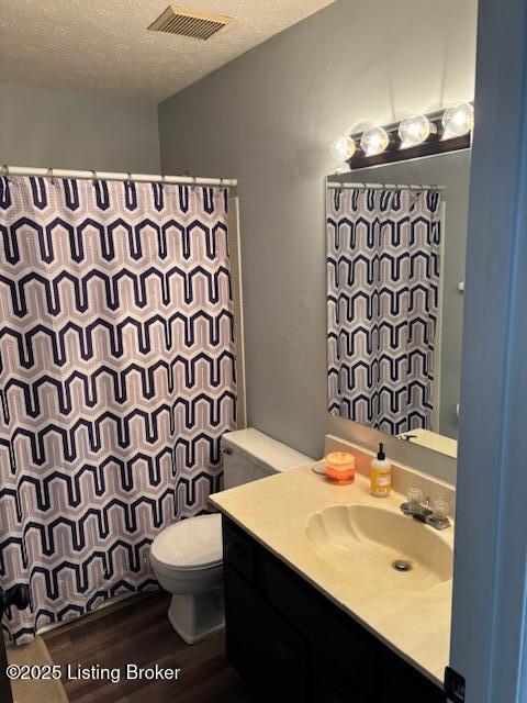 bathroom with hardwood / wood-style floors, vanity, a textured ceiling, and toilet