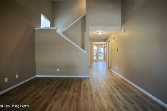 interior space with a towering ceiling and dark hardwood / wood-style floors