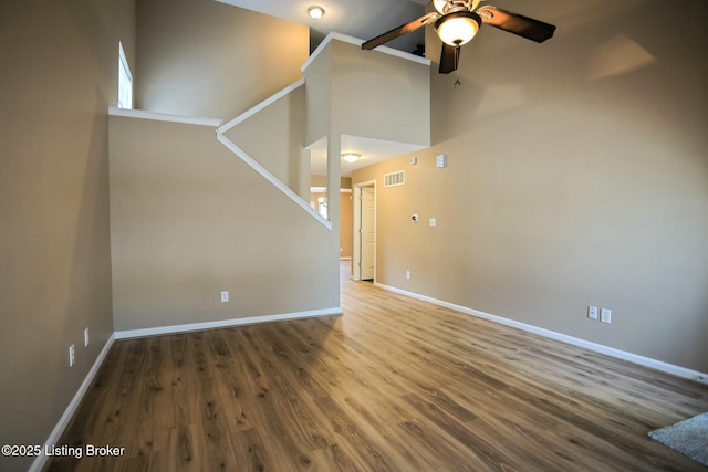 unfurnished living room featuring high vaulted ceiling, ceiling fan, and dark wood-type flooring