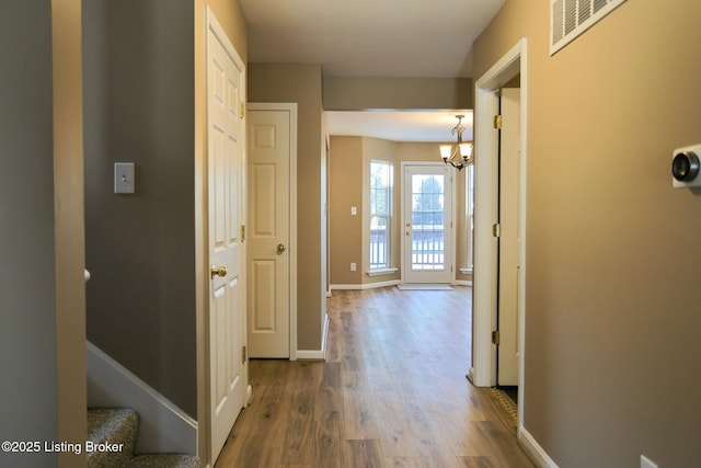 corridor featuring a notable chandelier and hardwood / wood-style floors