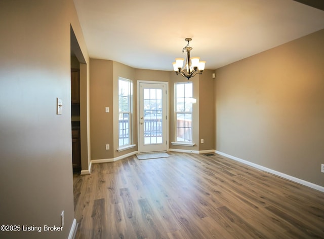 unfurnished room featuring dark wood-type flooring and a notable chandelier