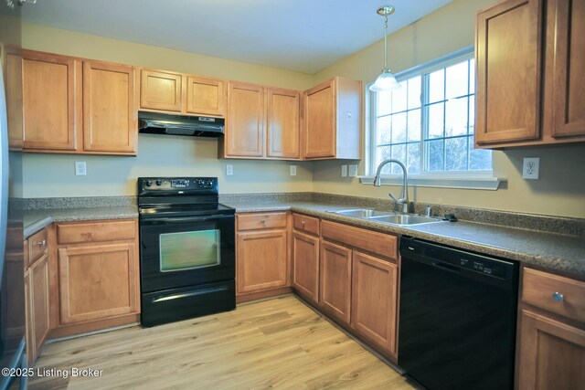 kitchen with black appliances, light hardwood / wood-style floors, decorative light fixtures, and sink