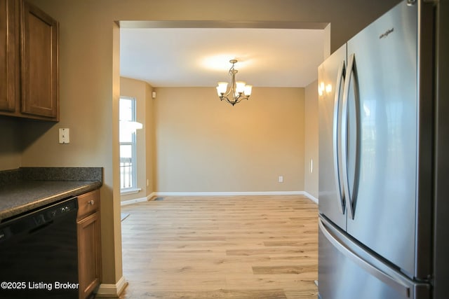 kitchen featuring decorative light fixtures, an inviting chandelier, black dishwasher, light hardwood / wood-style flooring, and stainless steel refrigerator