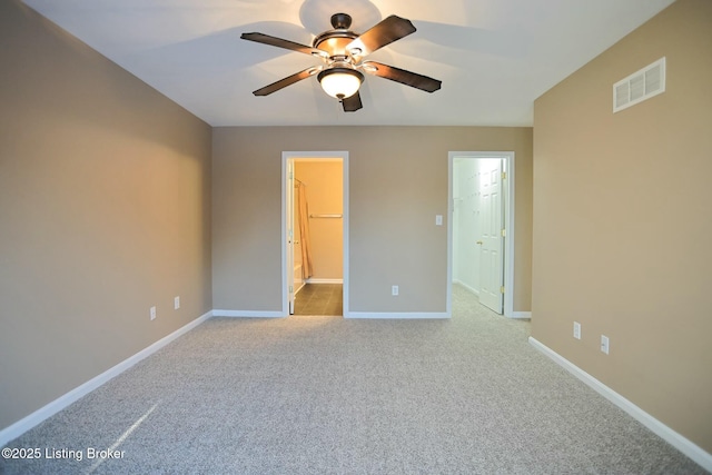 unfurnished bedroom with a walk in closet, light carpet, a closet, and ceiling fan