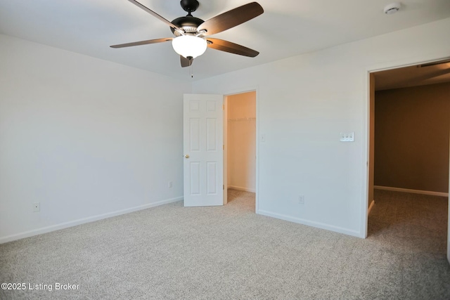 unfurnished bedroom featuring a walk in closet, light colored carpet, ceiling fan, and a closet