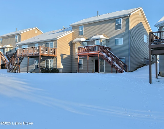 snow covered house with a wooden deck