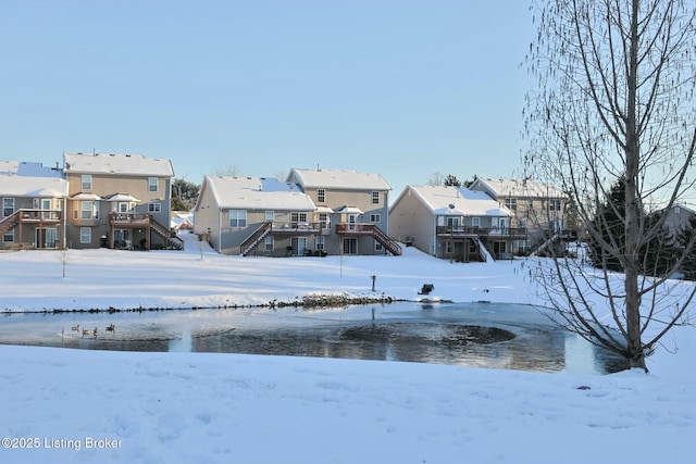 snowy yard featuring a deck with water view