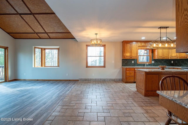 kitchen with pendant lighting, sink, tasteful backsplash, light hardwood / wood-style floors, and light stone counters