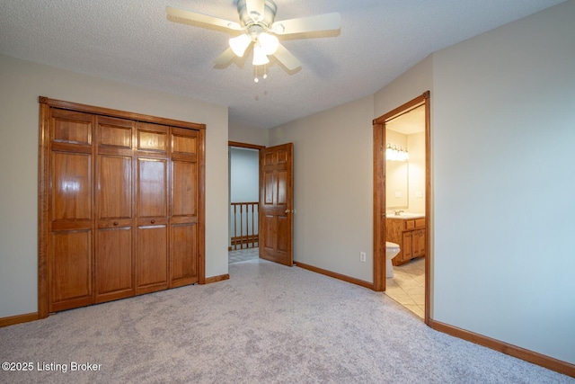 unfurnished bedroom with ceiling fan, a closet, light carpet, and a textured ceiling