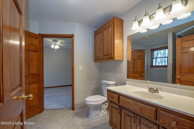 bathroom featuring ceiling fan, tile patterned flooring, a textured ceiling, toilet, and vanity