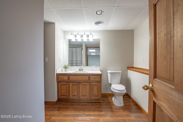 bathroom with a paneled ceiling, vanity, and toilet