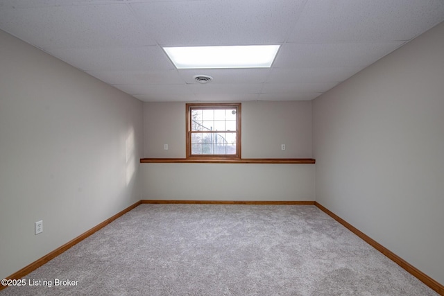 carpeted empty room with a drop ceiling