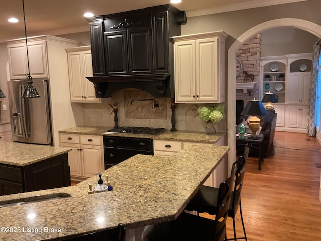 kitchen with crown molding, custom exhaust hood, backsplash, a breakfast bar area, and stainless steel appliances