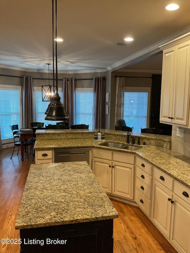 kitchen with a center island, black dishwasher, sink, ornamental molding, and light wood-type flooring