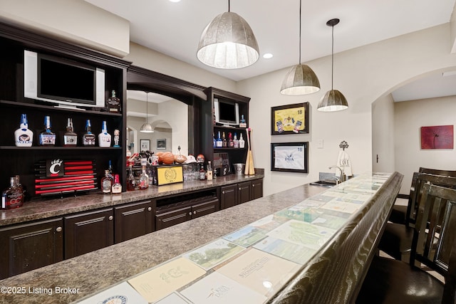 bar featuring dark brown cabinetry and pendant lighting