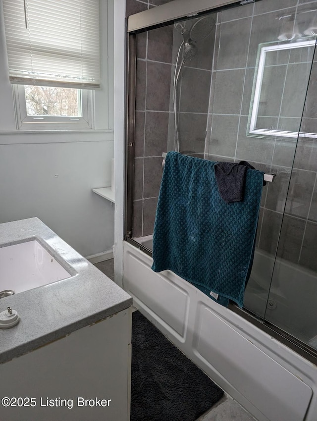 bathroom featuring combined bath / shower with glass door and vanity