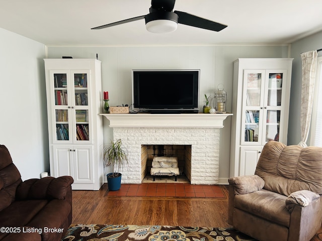 living room with a fireplace, ceiling fan, and dark wood-type flooring