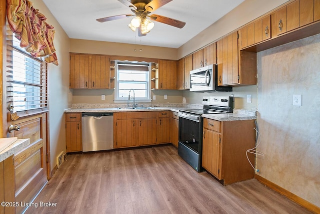 kitchen with ceiling fan, stainless steel appliances, sink, and wood-type flooring