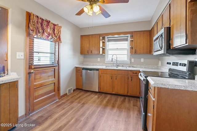 kitchen with sink, a wealth of natural light, light hardwood / wood-style floors, and appliances with stainless steel finishes