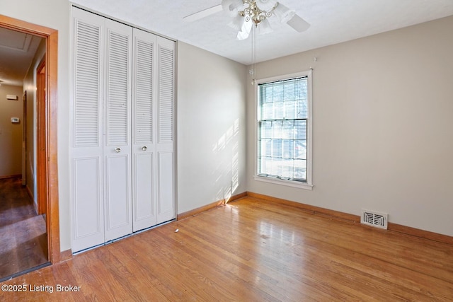 unfurnished bedroom with wood-type flooring, ceiling fan, and a closet