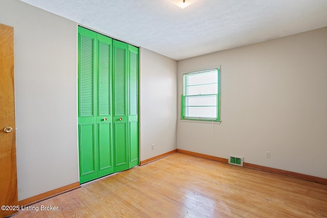 unfurnished bedroom with a closet, a textured ceiling, and light wood-type flooring