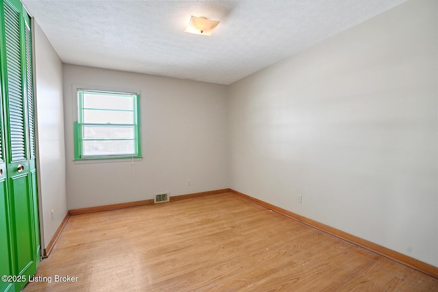 spare room with light hardwood / wood-style flooring and a textured ceiling