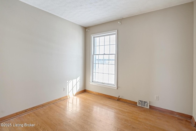 unfurnished room with light hardwood / wood-style flooring and a textured ceiling