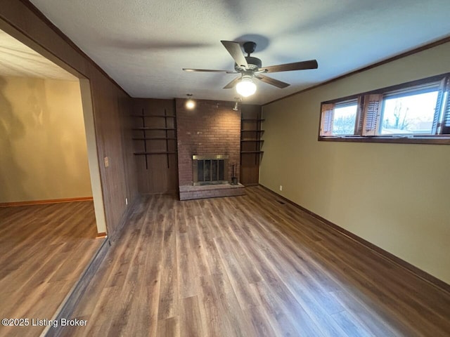 unfurnished living room featuring hardwood / wood-style flooring, ceiling fan, a brick fireplace, and a textured ceiling