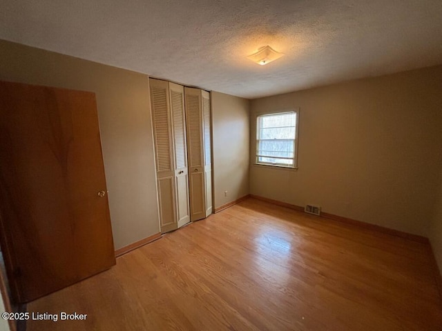 unfurnished bedroom featuring a closet, light hardwood / wood-style floors, and a textured ceiling