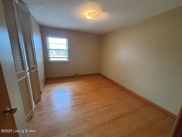 unfurnished room with light hardwood / wood-style flooring and a textured ceiling