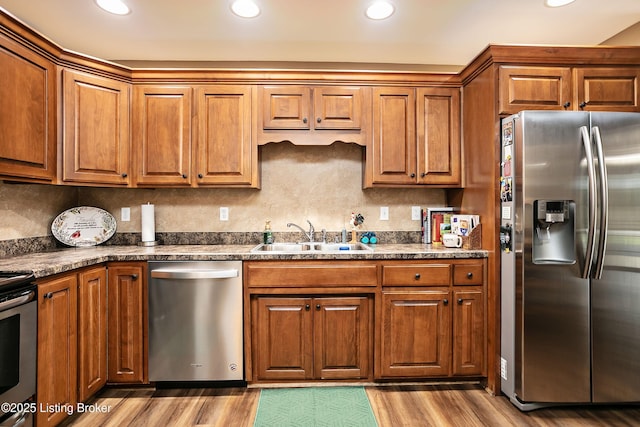 kitchen featuring stainless steel appliances, sink, light hardwood / wood-style flooring, and backsplash