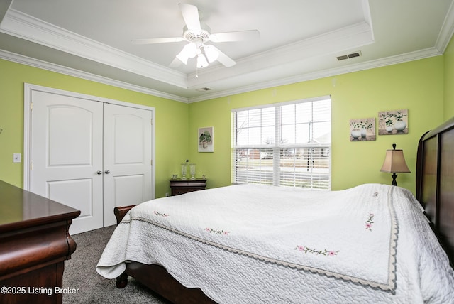 carpeted bedroom featuring a raised ceiling, ornamental molding, a closet, and ceiling fan