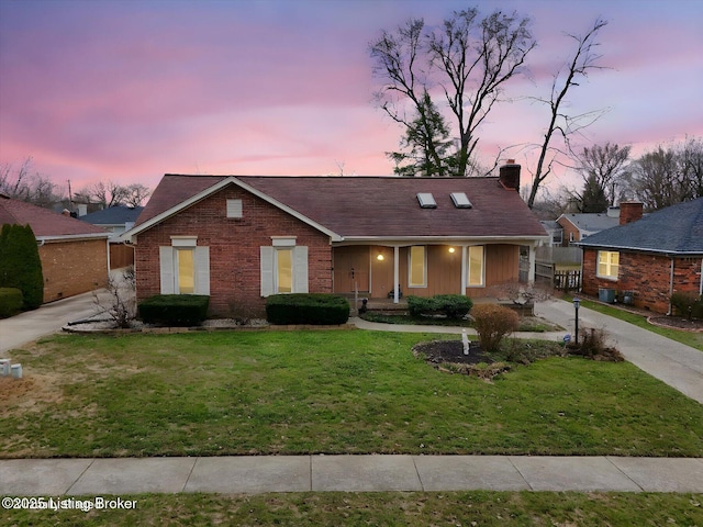 ranch-style home with brick siding, concrete driveway, a chimney, and a front lawn