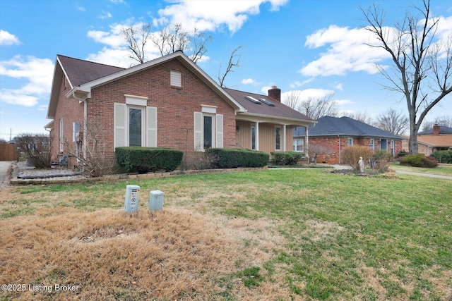 view of front of home featuring a front yard, brick siding, and a chimney