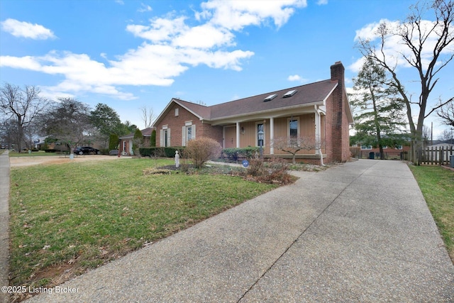 view of front of home with brick siding, a front yard, covered porch, a chimney, and driveway