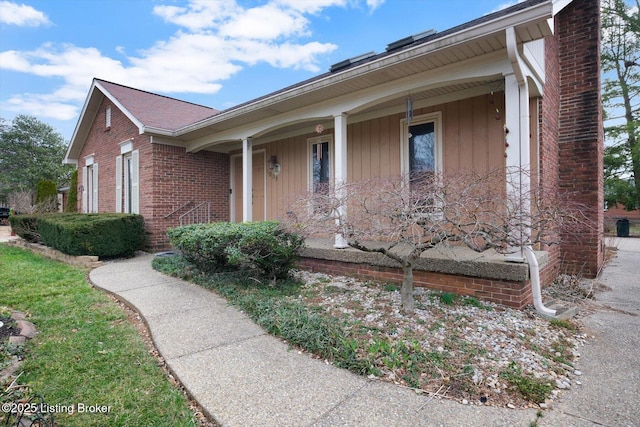 view of front of property with brick siding, covered porch, and a chimney