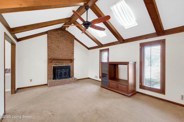 unfurnished living room with vaulted ceiling with skylight, light colored carpet, baseboards, and ceiling fan