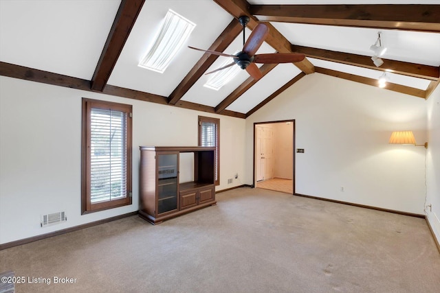 unfurnished living room with visible vents, beam ceiling, a ceiling fan, a skylight, and light colored carpet